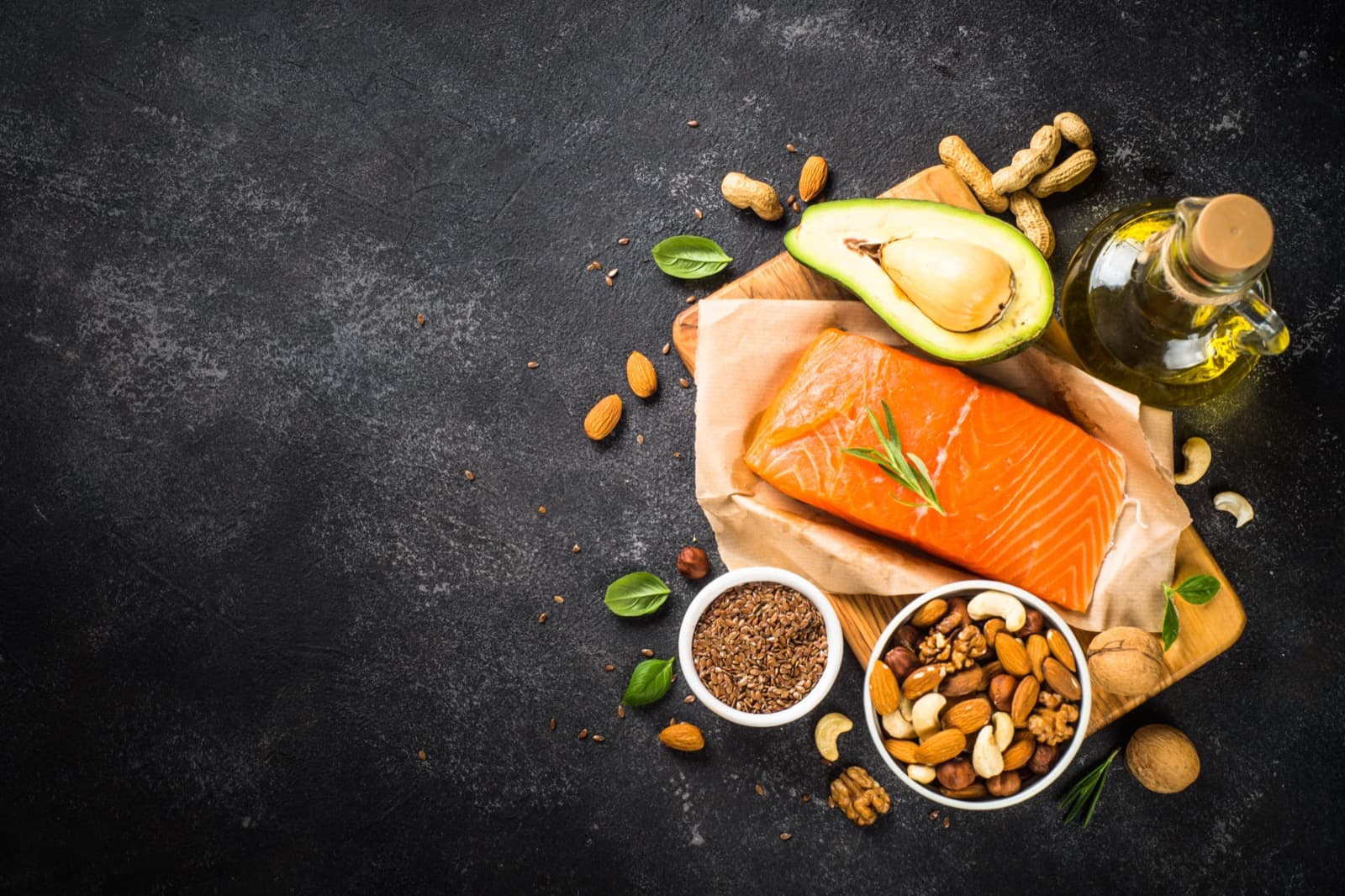 A plate of salmon, avocado, nuts, and olive oil on a dark slate, echoing the diet adjustments the doctor has described